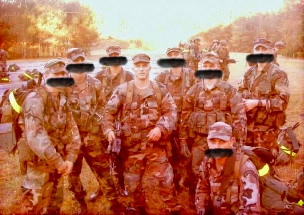 Soldiers in woodland camouflage pose outdoors, with black bars obscuring most of their faces.